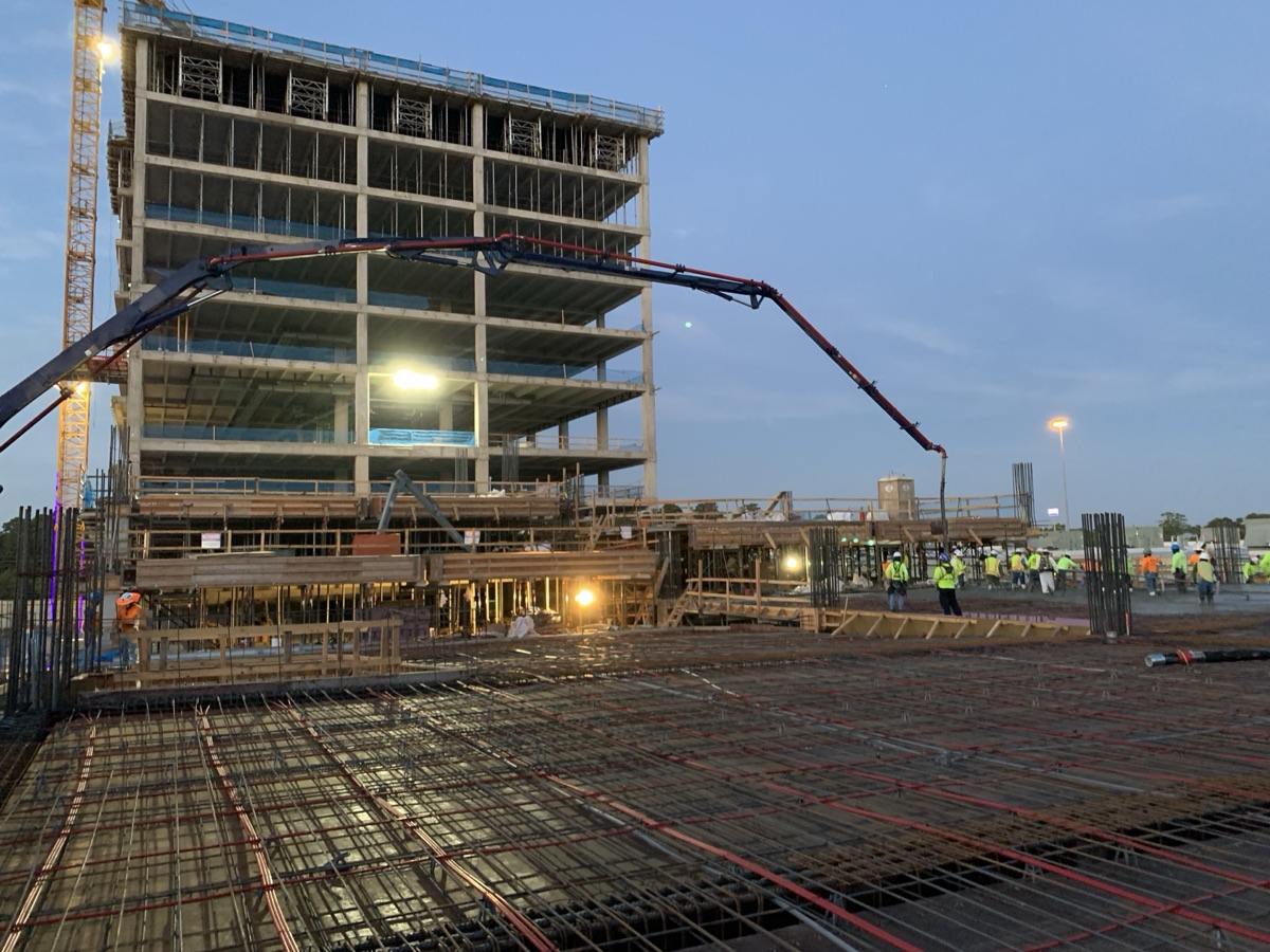 Dusk concrete pour with boom pump over rebar deck on a Harvey Builders high-rise project