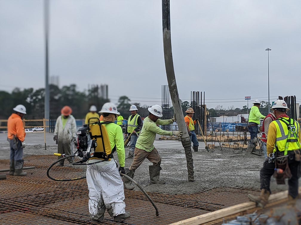 Construction workers pouring concrete on a slab at a construction site. - Senytec